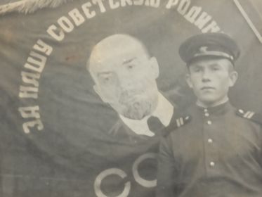 Гвардии младший сержант Сибгатуллин А.Н. на фоне боевого Знамени части